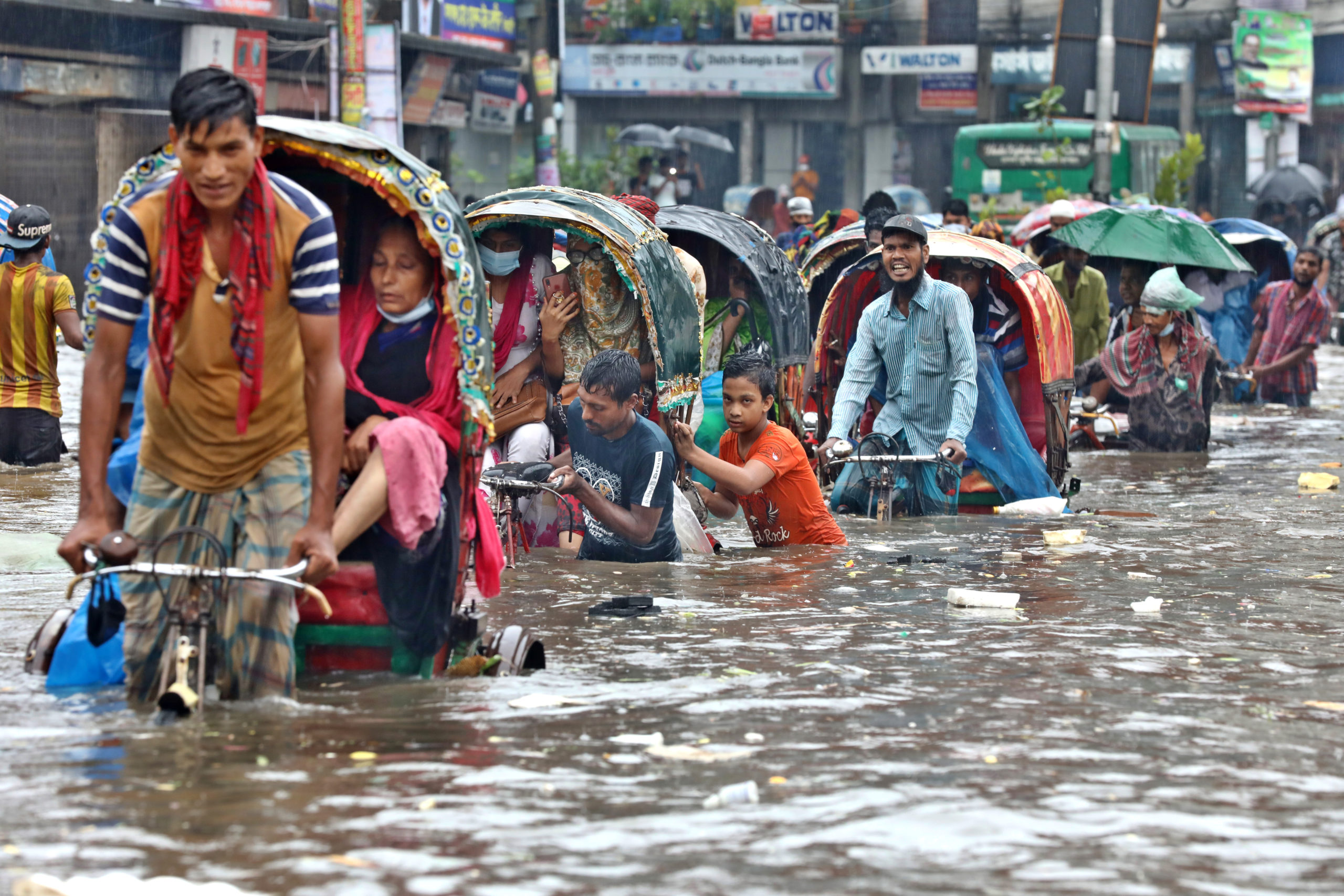 Bicycle rickshaws try to drive through a flooded street in Dhaka.